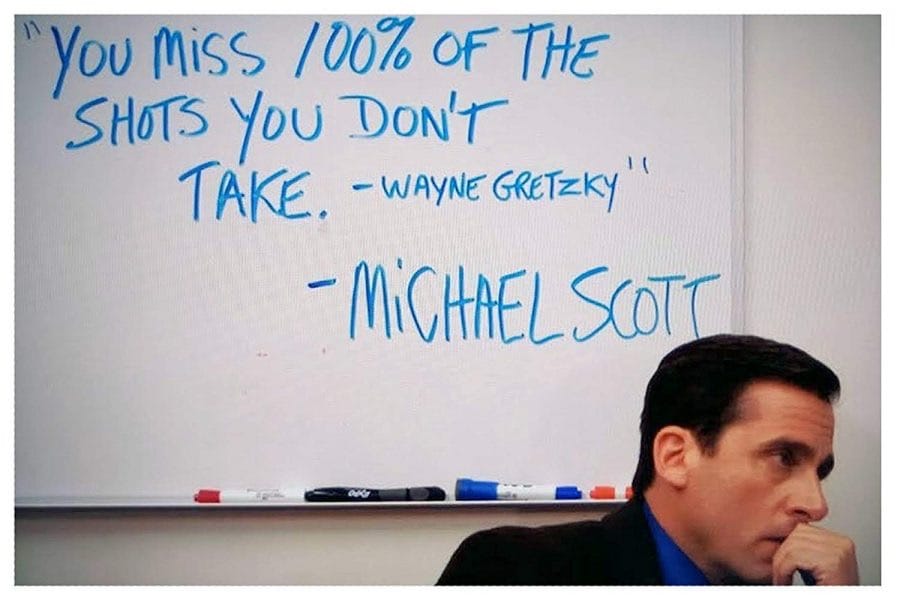 Steve Carell, as Michael Scott from "The Office," poses in front of a whiteboard. On the whiteboard is written: "You miss 100% of the shots you don't take. -Wayne Gretzky" -Michael Scott